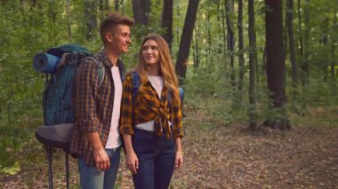 Bir çift canlı bir ormanda birlikte durur, açık havada kucaklaşırken gülümserler. Günlük yürüyüş kıyafetleri giymişler, doğaları gereği macera ve keşfe çıkmaya hazırlar..