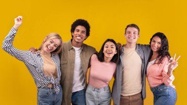 Uluslararası öğrencilerin dostluğu ve farklı ırk öğrencileri. Mutlu gençler farklı kişilerdir. Sarılma, jest ve sevinç duygularını ifade etme turuncu arka planda izole edilmiş, stüdyo çekimlerinde, boş alanlarda.