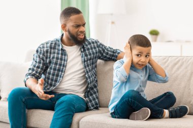 Evdeki koltukta oturup, kulaklarını tıkarken, Kara Baba 'nın mutsuz oğluna bağırmasına sinir oldum. Çocuğa Aile İçi Şiddet, Kötü Aile İlişkisi Problemi. Seçici Odaklanma