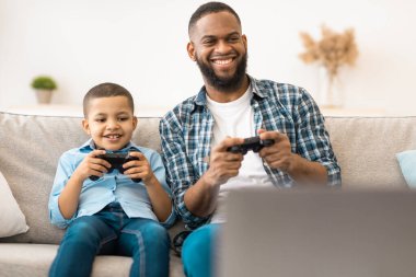 Kara Baba ve Oğlu 'nun bilgisayar oyunu oynaması ve hafta sonları evde koltukta oturup eğlenmesi heyecan verici. Genç baba, çocukla vakit geçirip eğleniyor. Aile Video Oyunları Reklamları