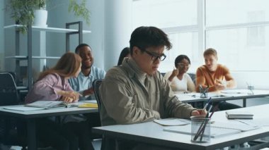 Çeşitli kolej öğrencileri, gözlüklü Asyalı sınıf arkadaşlarına zorbalık edip dedikodu yapıyorlar.