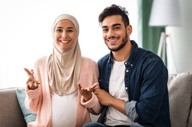 Mutlu haberler. Mutlu Müslüman çift kamerada konuşuyor, hamile ya da bebek cinsiyetini bildiriyor evde koltukta otururken mutlu İslami eşler gülümsüyor ve gelecekteki ebeveynliğin tadını çıkarıyorlar.
