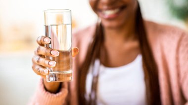 Unrecognizable Black Woman Offering Glass Of Water To Camera, Positive Young African American Female Recommending Healthy Refreshing Drink For Body Hydration, Closeup Shot, Cropped Image