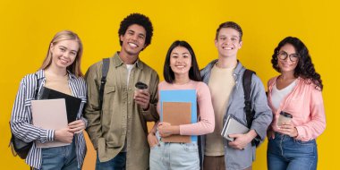 Farklı ülkelerden modern öğrenciler ve değişim programı. Sırtında kahve, kitap ve sırt çantalarıyla gülümseyen uluslararası genç insanlar, turuncu arka planda izole edilmiş kameraya bakıyorlar.