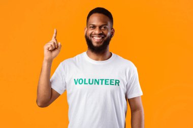 Harika bir fikir. Afrikalı Amerikalı Gönüllü Adam, Sarı Stüdyo Arkaplanının Üzerinde Gülümseyen Kamera 'yı Gösteriyor. Erkek eylemci Eureka anı yaşıyor. Gönüllü Reklam