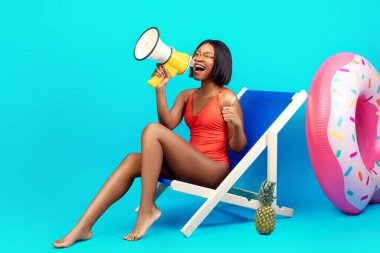 İnanılmaz bir teklif. Mayolu genç siyahi kadın şezlongda oturuyor, plaj tatili yapıyor, megafona bağırıyor, duyuru yapıyor, ürününüzün veya servisinizin reklamını yapıyor, mavi arka plan.