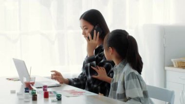 Parlak bir mutfakta, bir anne telefonda konuşurken kızı merakla izlerken, çocuğun ilgiye ihtiyacı var.