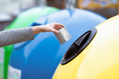 Çöp Ayıklama Konsepti. Kadın el yapımı metal kutuları sarı geri dönüşüm kutusuna atıyor, tanınmayan kadın atık geri dönüşüm sisteminden hoşlanıyor, seçici odaklı kırpılmış görüntü.