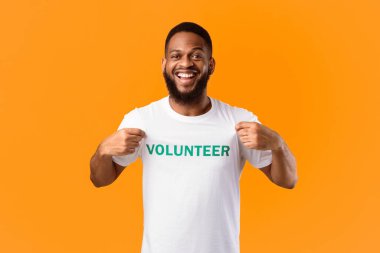 Gönüllü portresi. Sarı Stüdyo Arkaplanındaki Gönüllü Yazı Tişörtünü Gösteren Mutlu Siyah Eylemci. Gönüllü İş Konsepti