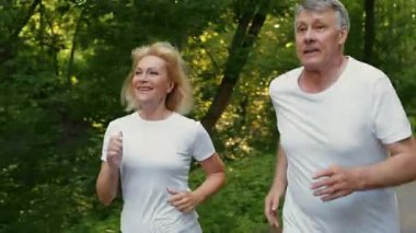 Kıdemli bir çift yemyeşil bir parkta mutlu mesut koşuyor, etkin bir yaşam tarzını kucaklıyor. Onların neşeli ifadeleri daha yaşlı yaşlarda formda kalmanın faydalarını yansıtıyor..