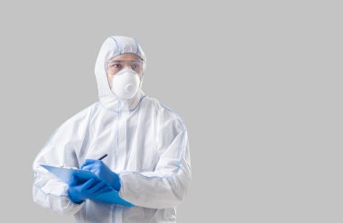 Koruyucu giysili, eldivenli ve gözlüklü Asyalı adam Coronavirüs hakkında veri yazıyor.