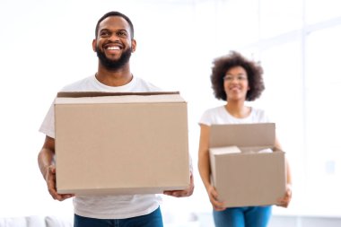 Yeni ev. Afrika kökenli Amerikalı Çift Taşındıktan sonra Karton Kutuları Taşıyarak Taşınıyor. Gayrimenkul kavramı. Genç Aile Konutları, Mülkiyet ve Satın Alım