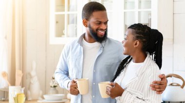 Romantik Afrikalı Amerikalı eşler mutfakta kahve içip sohbet ediyorlar. Neşeli Siyah Milenyum Çifti Sıcak Kafein İçkileri İçiyor ve Evlerinde birlikte vakit geçirmenin tadını çıkarıyor, Boşluğu Kopyalamak