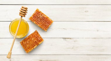 Tatlı ballı kavanoz ve beyaz ahşap arka planda bal petekleri, üst manzara, boşluğu kopyala