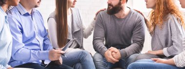 Rehabilitasyon grubu toplantısı. Kadınlar destek terapisinde, panoramada stresli erkekleri rahatlatıyor.