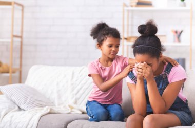 Samimi çocuk desteği. Küçük Afrikalı kız, ağlayan genç kız kardeşini ilişki problemleriyle teselli ediyor.