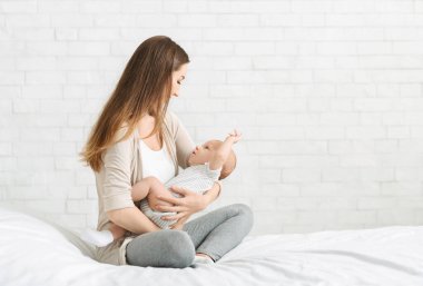 Anne ve çocuk bağlantısı. Milenyum annesi kucağında yeni doğmuş bir bebekle yatakta oturuyor.