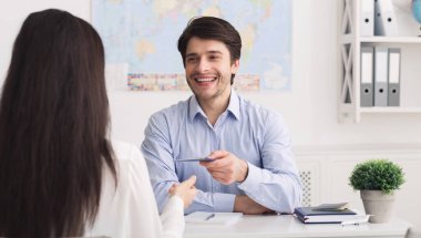 Vize alıyorum. Erkek seyahat acentesi ofiste turist için pasaport veren