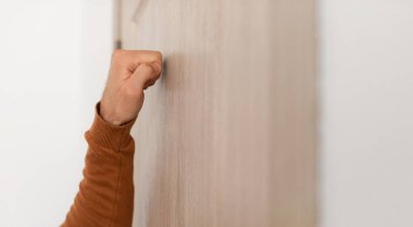 Yakından bakınca, tanınmayan genç bir adam ahşap kapıyı çalıyor, erkek ziyaretçi girişte bekliyor, misafir gelmek istiyor, bedava fotokopi alanı, seçici odak noktası yumruklar, panorama afişi.