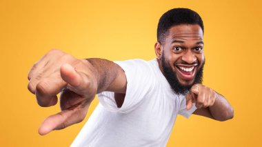 Sırada sen varsın. Stüdyoda sarı arka planda poz veren komik Afrikalı bir adam. Senin konseptini seçiyorum, reklam afişi ve neşeli siyah adam.