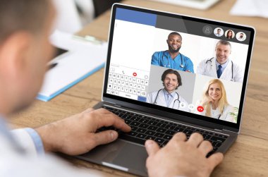 Bilgisayarının başında iş arkadaşlarıyla çevrimiçi görüntülü konuşma yapan bir doktor. Çevrimiçi Klinik Danışmanlık, Uzaklık Tıbbi Konferansı. Seçici Odaklanma, Kırpılmış, Kolaj