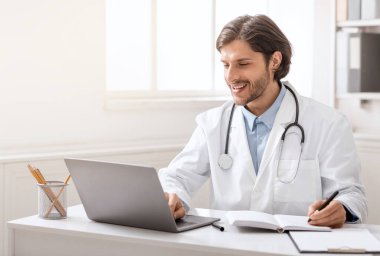 Çevrimiçi uzlaşma. Genç doktor iş arkadaşlarıyla çevrimiçi dizüstü bilgisayarla konuşuyor, boş alan