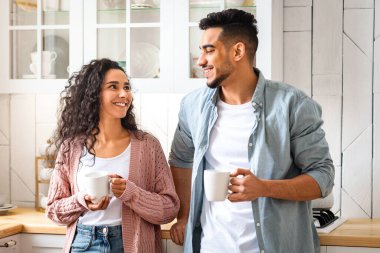 Romantik genç Arap eşlerin portresi. Mutfakta sabah kahvesi içiyorlar. Milenyum Orta Doğulu erkek ve kadın sıcak içeceklerden zevk alıyorlar.