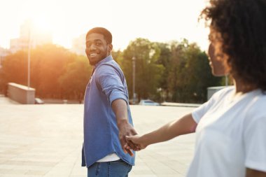 Takip et beni. Kız arkadaşı aşağıdaki erkek arkadaşı el tutarak, gün batımı şehirde yürüyüş