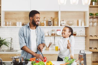Afro baba ve küçük kızı, birlikte yemek pişiriyor. Anne konsepti için yemek pişirme
