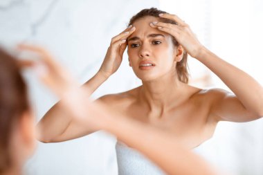 Sivilce sorunu. Hüsrana uğramış Bayan Alnına Sivilce Sıkarak Aynada Yansımaya Bakıyor Modern Tuvalette İçerde Duruyor. Yüz derisi problemleri, sivilce sorunu konsepti. Seçici Odaklanma