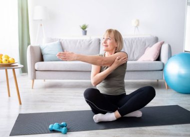 Sportif son sınıf öğrencisi kadın evinde kolunu paspasa uzatıyor, kopyalama alanı. Esneklik egzersizleri yapan, yoga yapan ya da evde pilates yapan çekici olgun bir kadın. Yurt içi eğitim kavramı