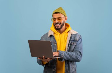 İnternette çalışan ve mavi stüdyo geçmişine bakan mutlu, genç, Arap, serbest çalışan bir adam. Teknoloji, harika web sitesi konsepti