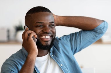 Mobil çağrı. Neşeli bir Afrikalı Amerikalı cep telefonuyla konuşuyor ve gülümsüyor, olumlu siyahi adam keyifli bir telefon görüşmesi yapıyor, modern iletişimin tadını çıkarıyor, seçici odaklı yakın plan portresi yapıyor.
