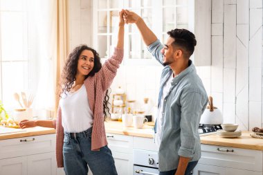 Mutlu Orta Doğulu Çiftler Mutfak İçi 'nde Dans Ediyor. Neşeli Arap aşıkları el ele tutuşuyor ve birbirlerine gülümsüyorlar, evde eğleniyorlar, hafta sonlarını birlikte geçiriyorlar, uzay kopyaları yapıyorlar.