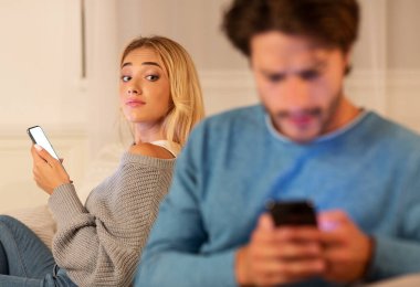 Hile İşaretleri. Erkek arkadaşına telefonla mesaj atıp sadakatsizlikşüphesi yla bakıyor evde kanepede oturuyor. Seçici Odak