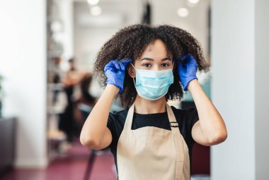 Kişisel hijyen. Güzellik hocası kuaförde çalışmadan önce koruyucu tıbbi maske takıyor.