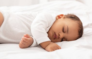 Şirin Afrikalı bebek evde gözleri kapalı bir şekilde, yan yatarak huzur içinde uyuyor. Küçük Bebek 'in Gündüz Uykusunda Dinlenen Yakınlığı.