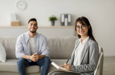 Başarılı tedavi konsepti. Kendine güvenen Arap kadın psikolog ve ofisteki etkili terapiden sonra gülümseyen genç adam. Orta Doğulu adamla seansta mutlu psikoterapist.