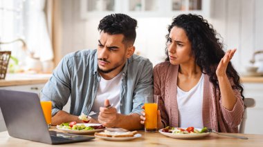 Mutfakta kahvaltı ederken dizüstü bilgisayarla kafası karışmış Arap Çifti, evde bilgisayar kullanırken Orta Doğu 'lu eşlerin kötü internet bağlantısından şikayet etmesinden rahatsız oldu