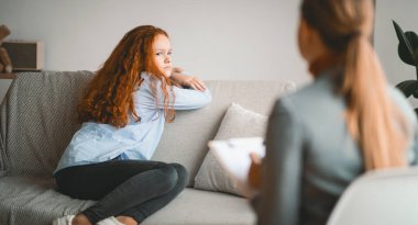 Stres ve psikolojik travma. Çocuk psikoloğu ofiste ya da evde endişeli bir kızla çalışıyor. Gençlerin geri dönmesinden korkuyor. Seans sırasında uzmanla konuşurken endişe duyuyor.