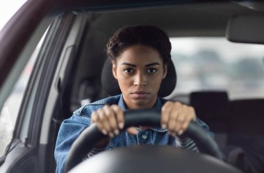 Yüz ifadesi, olumsuzluk, stres ve trafik sıkışıklığı. Ciddi şekilde üzgün genç Afrikalı Amerikalı bir bayan direksiyonun arkasında oturuyor ve pencereye doğru gergin bir şekilde bakıyor.