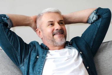 Mutlu sakallı son sınıf öğrencisi rahat rahat kanepede oturup fotokopi odasına bakıyor. Rahat olgun bir adam oturma odasında kanepede dinleniyor ve müreffeh bir hayat hayal ediyor.