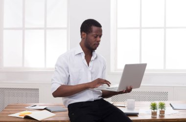 Modern beyaz ofis içinde laptop ile siyah işadamı çalışın. kopya alanı