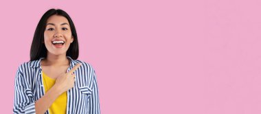 Harika bir teklif. Gülümseyen Asyalı genç kadının portresi pembe stüdyo arka planında fotokopi alanını işaret ediyor. Reklam metinleri ve reklam metinleri için bedava yer gösteren ve sunan neşeli bayan, afiş