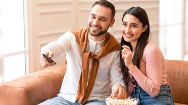 Aile Hafta Sonu Tatili. Televizyonda film seyreden modern Arap çift evdeki koltukta oturmuş patlamış mısır yiyor. Mutlu Ortadoğu eşleri evde birlikte vakit geçirmekten zevk alıyor. Televizyon Programlama