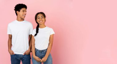 Pembe stüdyo arka planında poz veren hoş bir genç çift.