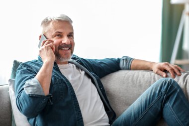 Gülümseyen son sınıf öğrencisinin telefon görüşmesi yapıp fotokopi odasına bakışının yan görüntüsü. Yakışıklı yaşlı adam evdeki kanepede dinleniyor, cep telefonuyla arkadaşlarıyla veya sevgilileriyle konuşuyor.