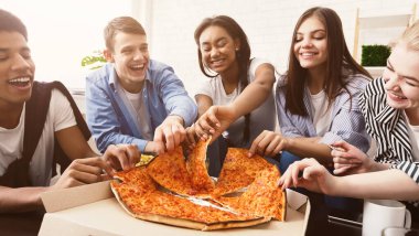 Atıştırma zamanı. Mutlu öğrenciler pizza yeme ve evde sohbet