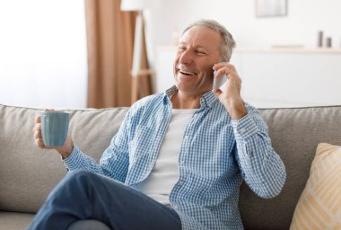 Oturma odasındaki koltukta oturan, aile veya arkadaşlarıyla gayri resmi görüşmeler yapan, kahve içen, cep telefonuyla konuşan neşeli yaşlı adamın portresi. Uzak İletişim