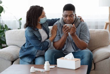 Tıbbi maskeli, evde Coronavirüs 'ten muzdarip hasta kocasıyla ilgilenen, ona çay ikram eden, bedava uzay sunan Afro Kadınları seven.